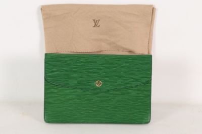 un gros plan sur un sac à main vert contenant une enveloppe beige