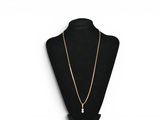 a black mannequin with a gold chain and a pearl pendant