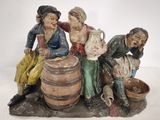 une figurine représentant trois personnes assises sur un tonneau