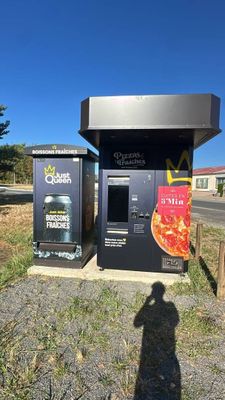 two vending machines sitting on the side of a road next to a parking lot