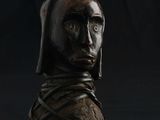 statue d'un homme portant une capuche, sur fond noir