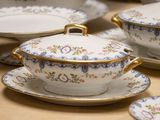 many plates and bowls on a table with gold trimming