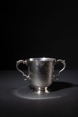 a silver cup on a black surface with a black background