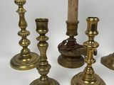 several brass candlesticks are lined up on a white surface