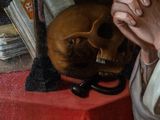 a painting of a man sitting at a table with a skull in front of him