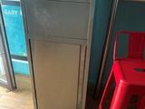 a red chair next to a silver refrigerator in a blue room