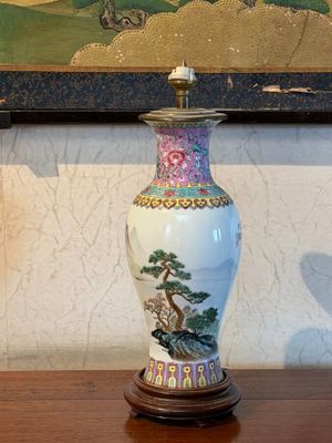 a vase sitting on a wooden table with a painting on the wall behind it