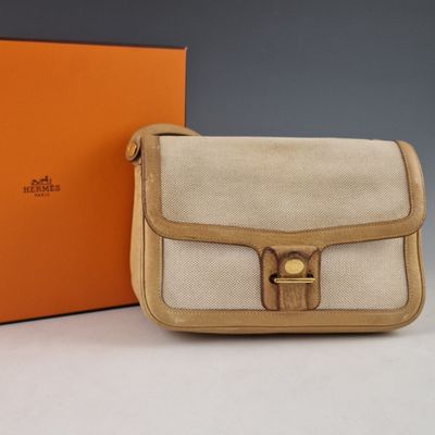 une boîte orange et blanche avec un sac à main beige et une boîte marron