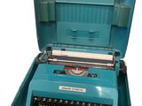 une vieille machine à écrire bleue avec son étui ouvert, sur fond blanc