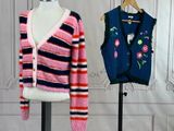 two sweaters on a mannequin stand in front of a white wall