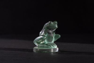 green glass figurine of a frog on a black background