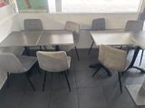 tables and chairs in a restaurant with a large window in the background