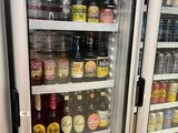 many bottles of beer on display in a refrigerator