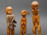 three wooden figurines of three men and a woman
