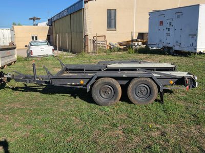 a trailer that is sitting in the grass in front of a building