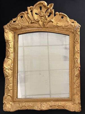 an ornate gold framed mirror on a black wall next to a window