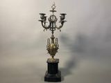 an antique brass candelab with four candles on a marble base