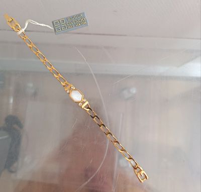 a gold bracelet with a white stone on it