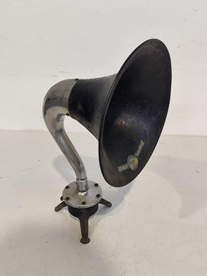 un gramophone ancien, noir et argenté, posé sur une surface blanche
