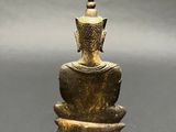 an old bronze buddha statue sitting on top of a table