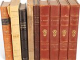 several old books are lined up in a row on a white surface