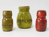 trois salières et poivrières de couleurs différentes posées sur une surface blanche