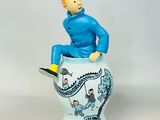 a figurine of a man sitting on top of a vase