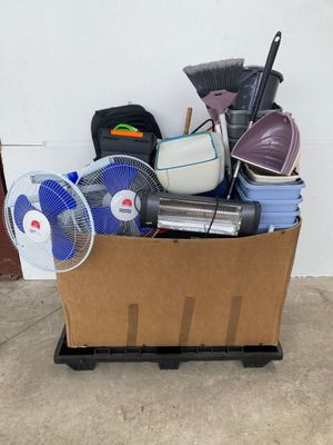 a cardboard box full of household items and a fan