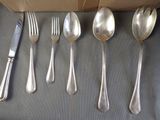 six spoons and six forks and a knife on a table