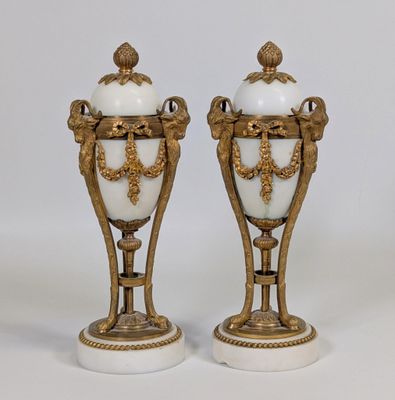 une paire de vases blancs et dorés posés sur des socles en marbre, sur fond blanc