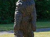 une statue représentant un ours debout sur un rocher, au milieu de l'herbe