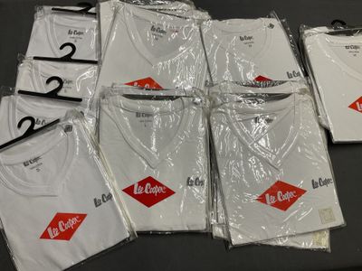 beaucoup de t-shirts emballés dans du plastique, posés sur une table