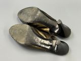 une paire de chaussures pour femme noires et dorées posées sur une surface blanche