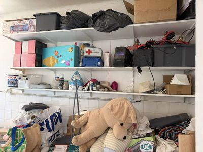 un ours en peluche posé sur une étagère dans une pièce encombrée
