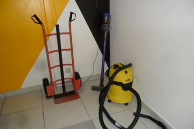 un aspirateur et un diable dans un coin de la pièce