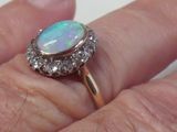 a person holding a ring with an oplite and diamonds on it