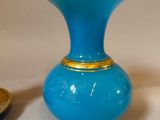 a blue vase with a gold rim sitting next to a saucer