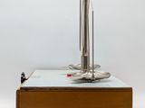 a metal object on a wooden table with a white background