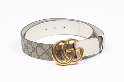 un gros plan d'une ceinture avec une boucle dorée sur fond blanc