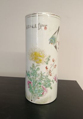 a white vase with flowers on it sitting on a table