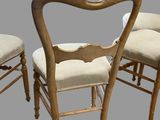 three wooden chairs with beige upholstered seats and a white cushion