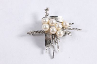 a silver brooch with pearls on it on a white surface