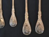 five silver spoons are lined up on a black surface