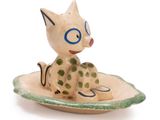 a small ceramic figurine of a cat sitting on a plate