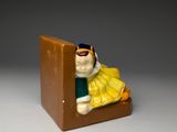 une petite figurine représentant une personne assise sur une chaise