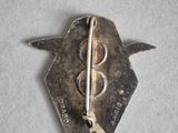 a silver pin that has a bird on it
