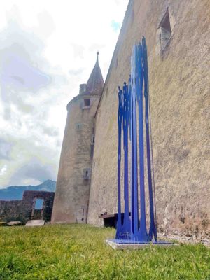 a tall blue sculpture in front of a stone building