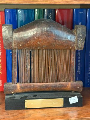 a wooden sculpture on a shelf with books in the background