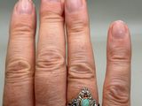 a woman ' s hand holding a ring with a stone in it