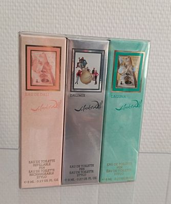 trois boîtes de parfum exposées sur une étagère en verre